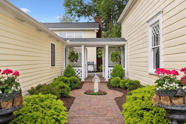 property entrance featuring a shingled roof and a chimney
