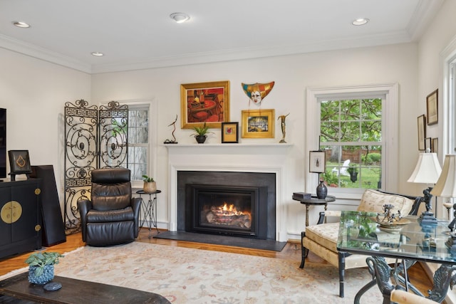 sitting room featuring crown molding, recessed lighting, a glass covered fireplace, and wood finished floors