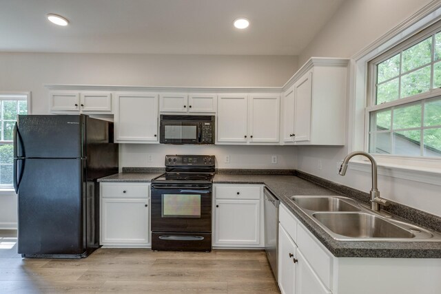 kitchen featuring dark countertops, a sink, white cabinets, black appliances, and recessed lighting