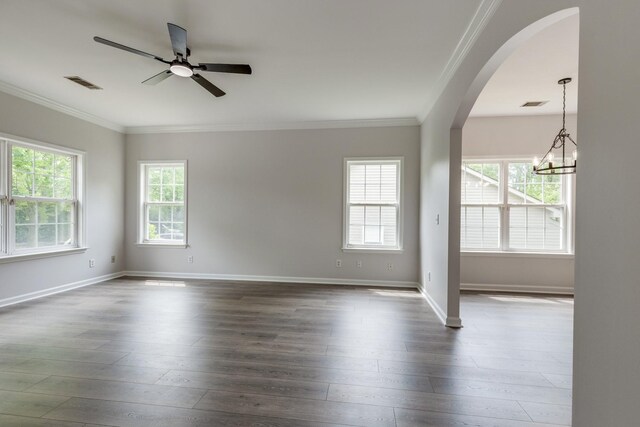 empty room featuring crown molding, arched walkways, visible vents, and dark wood-style floors