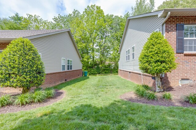 view of property exterior featuring brick siding, a yard, and crawl space