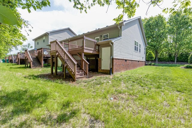 rear view of house featuring stairs, a lawn, and a wooden deck