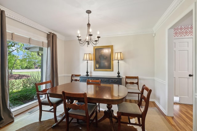 dining room with ornamental molding, light wood finished floors, and a chandelier