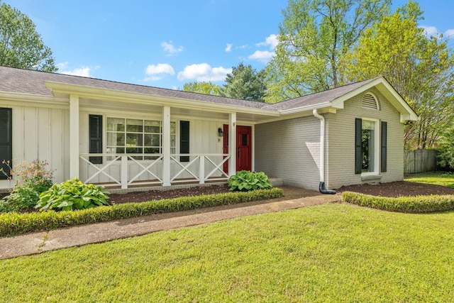 ranch-style house with a front lawn, brick siding, a shingled roof, board and batten siding, and a porch