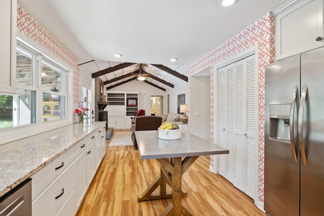 kitchen with light stone countertops, stainless steel refrigerator with ice dispenser, vaulted ceiling with beams, light wood-type flooring, and white cabinets