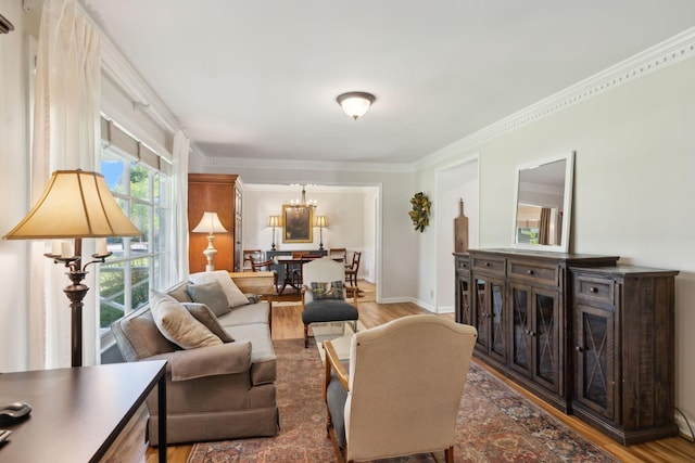 living area featuring crown molding, baseboards, wood finished floors, and a chandelier