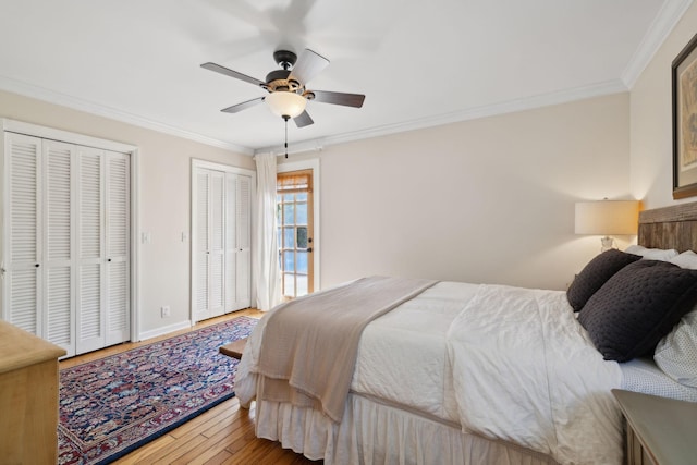 bedroom featuring multiple closets, ornamental molding, baseboards, and wood finished floors