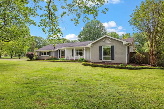 ranch-style house with fence, covered porch, a front yard, brick siding, and board and batten siding