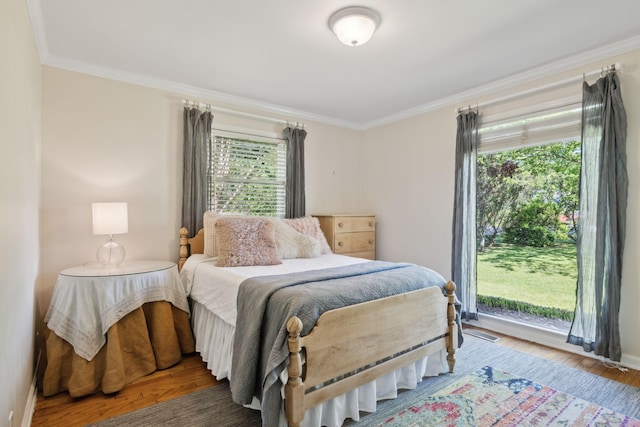 bedroom featuring crown molding, multiple windows, wood finished floors, and visible vents