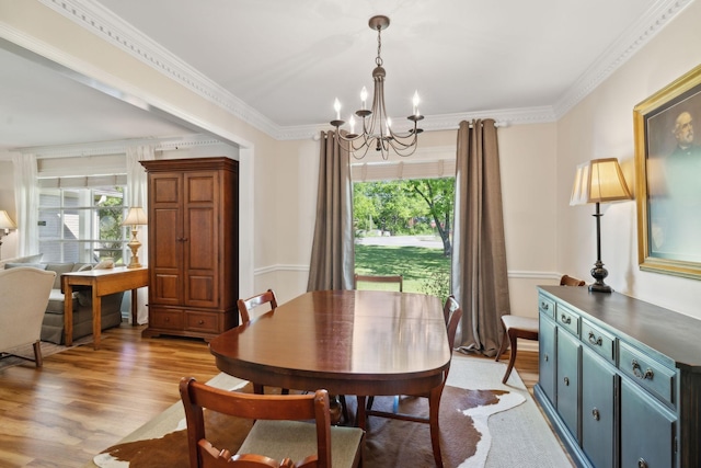 dining space with a notable chandelier, ornamental molding, a healthy amount of sunlight, and light wood-style flooring