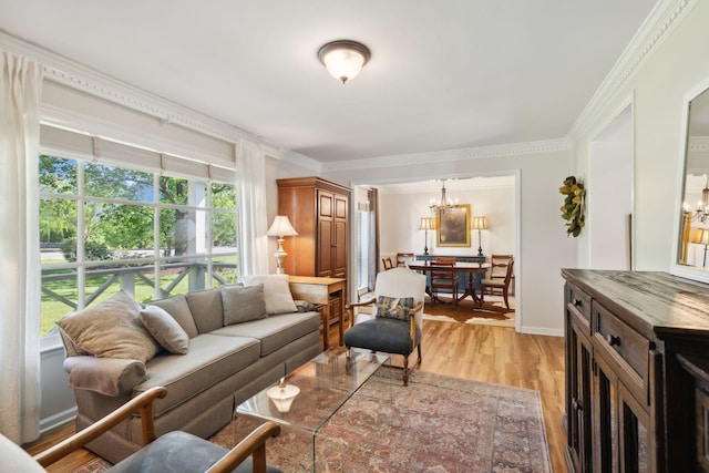 living room with crown molding, baseboards, a chandelier, and light wood-type flooring
