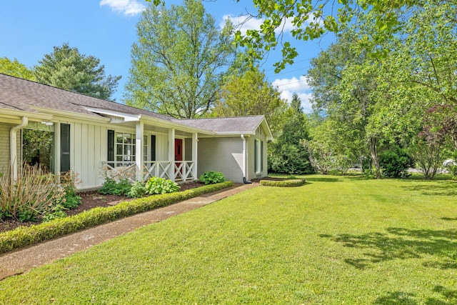 view of property exterior featuring a lawn, a shingled roof, board and batten siding, and covered porch