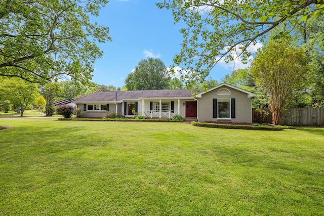 single story home with a porch, brick siding, fence, and a front yard
