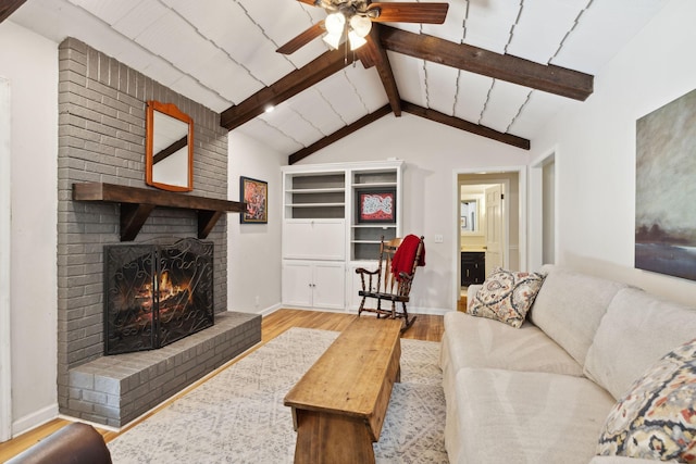 living room featuring ceiling fan, a brick fireplace, baseboards, vaulted ceiling with beams, and wood finished floors