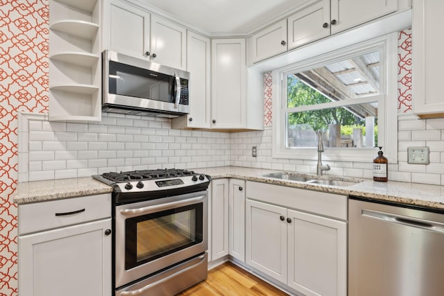 kitchen with open shelves, appliances with stainless steel finishes, decorative backsplash, and a sink