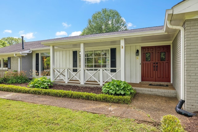 view of exterior entry with board and batten siding, a shingled roof, and covered porch