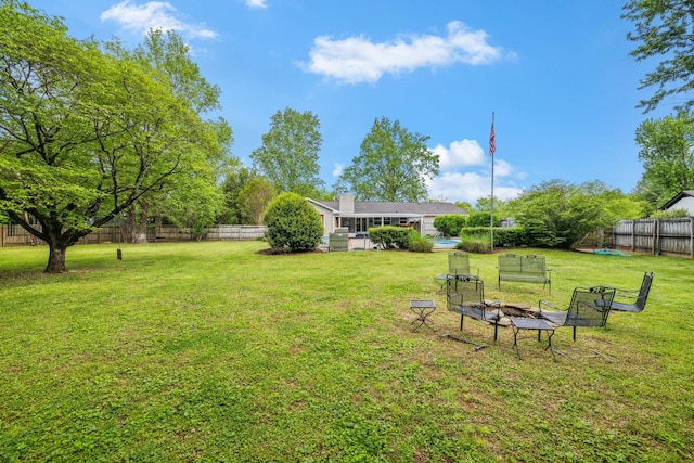 view of yard featuring a fenced backyard and a fire pit
