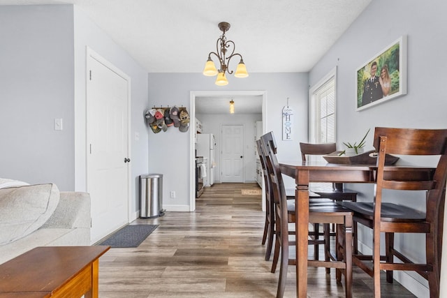 dining space featuring baseboards, wood finished floors, and a chandelier