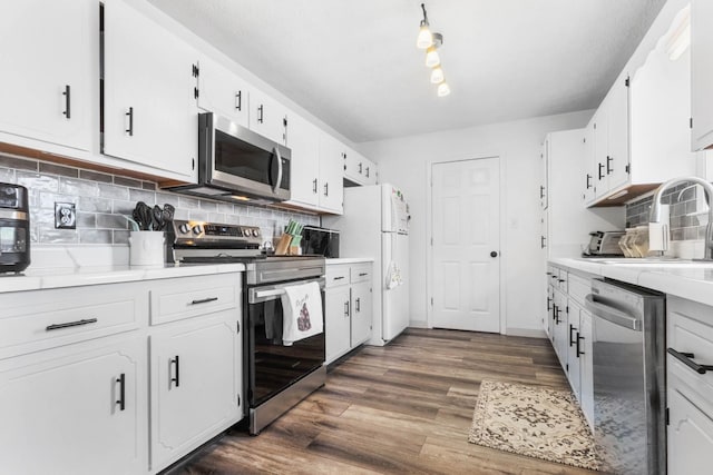 kitchen featuring light countertops, appliances with stainless steel finishes, white cabinets, and dark wood-style flooring