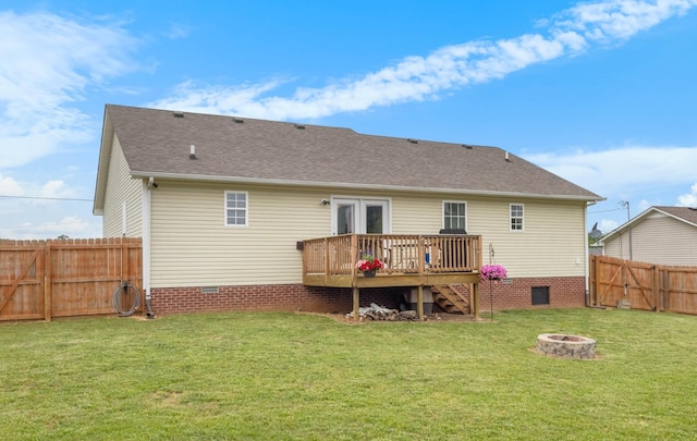 rear view of house with crawl space, a lawn, a wooden deck, a fenced backyard, and a fire pit