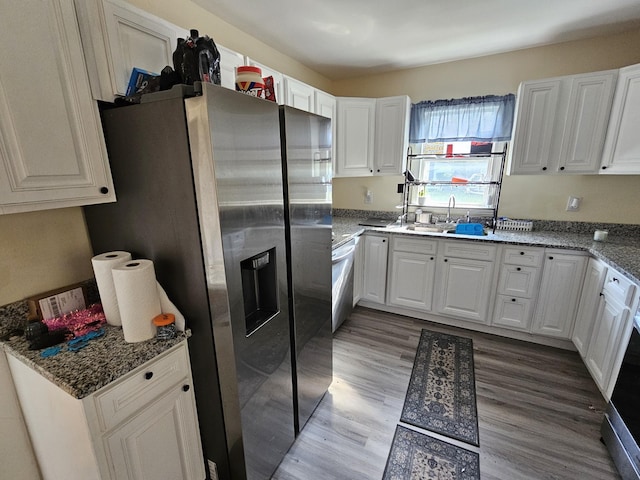 kitchen with light wood-type flooring, dishwasher, a sink, stainless steel fridge with ice dispenser, and white cabinetry