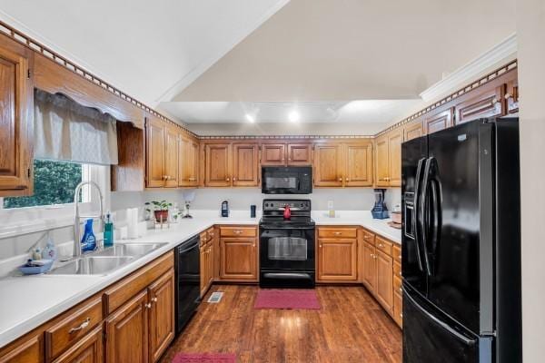 kitchen featuring a sink, dark wood finished floors, black appliances, and light countertops