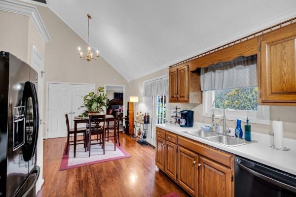 kitchen featuring brown cabinetry, light countertops, black refrigerator with ice dispenser, and dishwasher