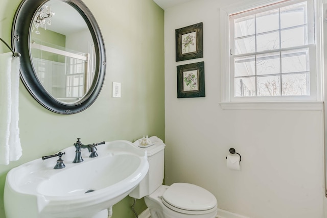 bathroom featuring toilet, baseboards, plenty of natural light, and a sink