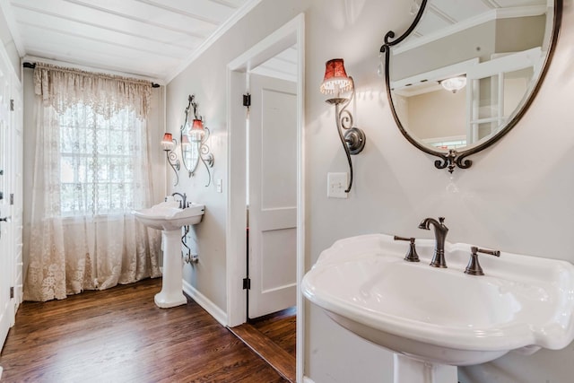 bathroom with baseboards, ornamental molding, a sink, and wood finished floors