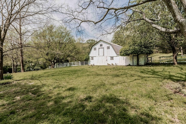 view of yard featuring a barn, an outdoor structure, and fence