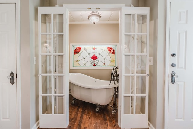 bathroom with crown molding, a freestanding tub, wood finished floors, and french doors