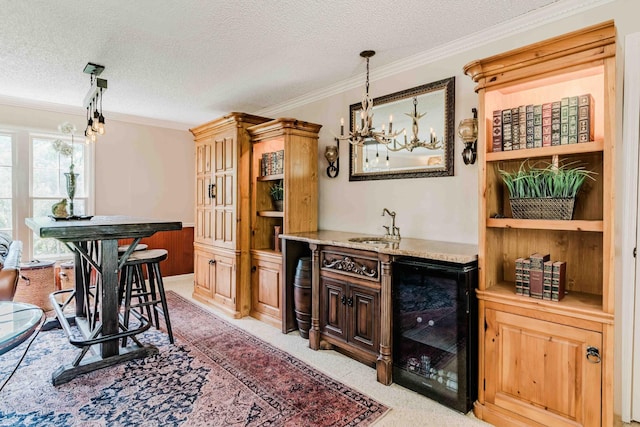 bar with an inviting chandelier, ornamental molding, beverage cooler, and a sink