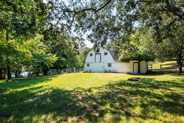 view of yard featuring a barn, fence, and an outdoor structure
