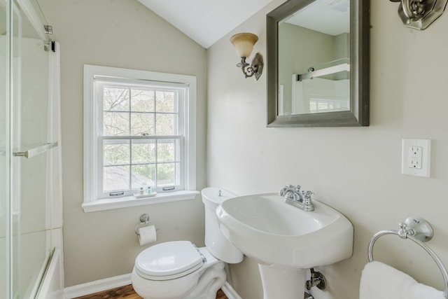 bathroom featuring a sink, baseboards, toilet, and lofted ceiling