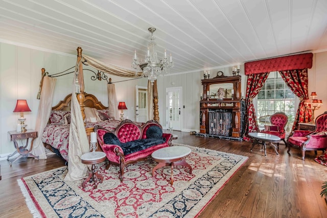 bedroom featuring an inviting chandelier, ornamental molding, a fireplace, and wood finished floors