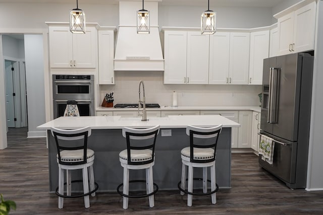 kitchen with custom exhaust hood, light countertops, white cabinets, backsplash, and stainless steel appliances