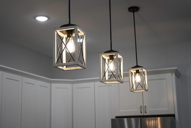 details featuring white cabinets, hanging light fixtures, and stainless steel refrigerator