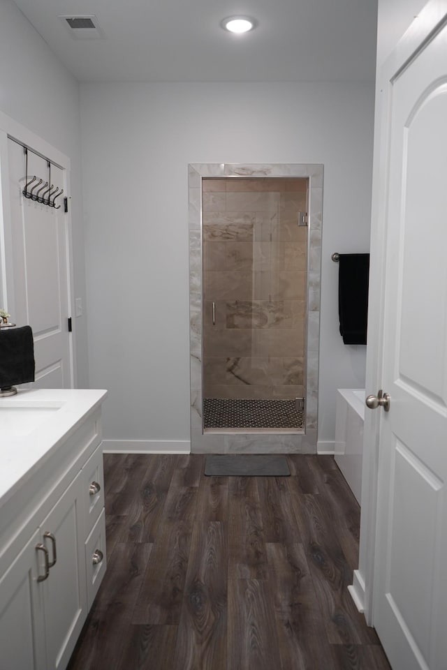 bathroom featuring a garden tub, visible vents, a stall shower, wood finished floors, and vanity