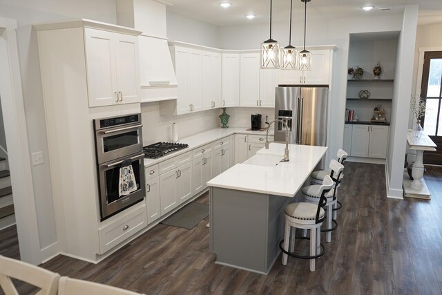 kitchen with a breakfast bar, dark wood-style floors, white cabinetry, a sink, and appliances with stainless steel finishes