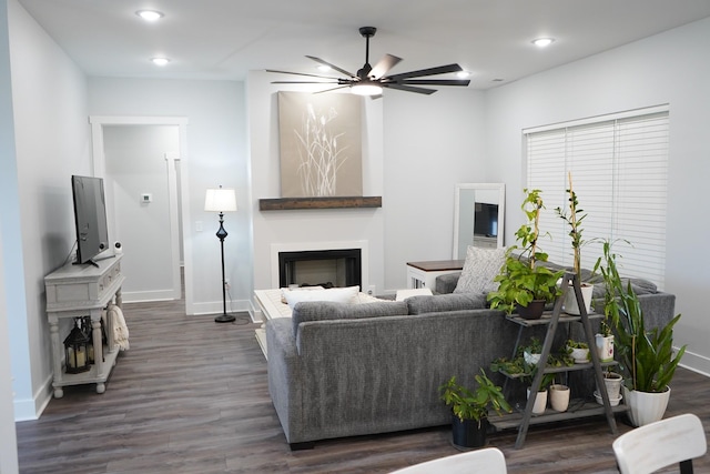 living room featuring baseboards, dark wood-style flooring, ceiling fan, and a fireplace