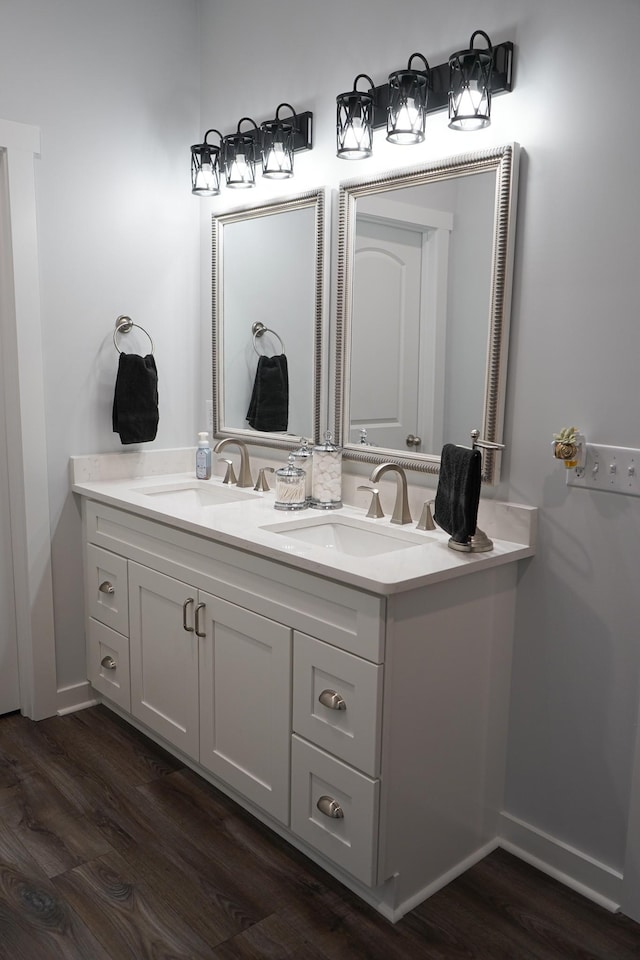 bathroom with double vanity, baseboards, a sink, and wood finished floors