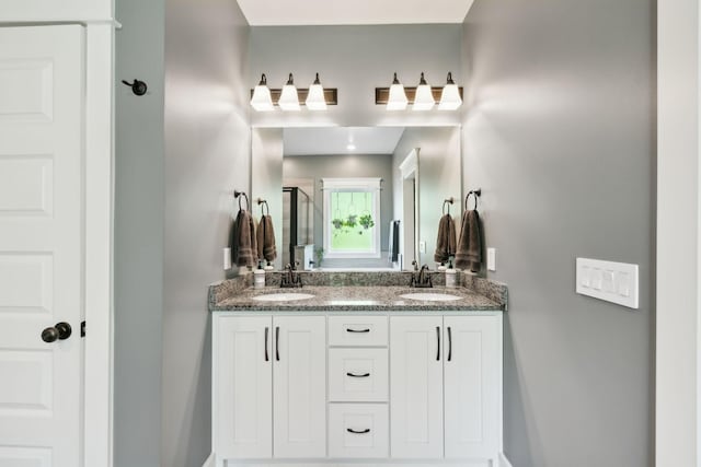 full bathroom with double vanity, a sink, and a stall shower