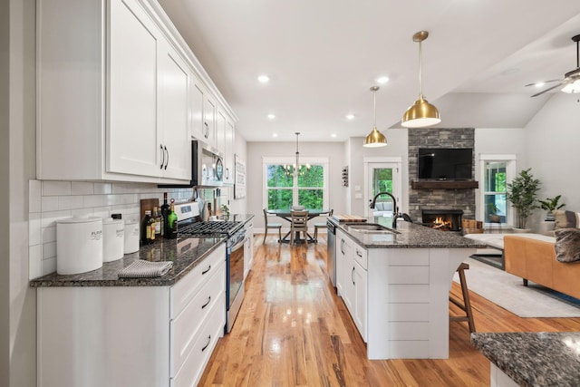 kitchen featuring a sink, white cabinets, open floor plan, and stainless steel appliances
