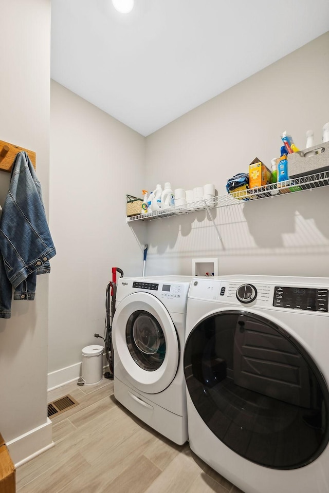 washroom featuring independent washer and dryer, laundry area, baseboards, light wood-type flooring, and visible vents