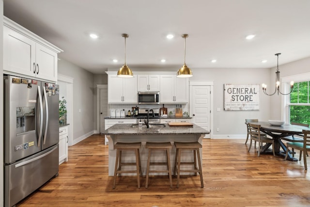 kitchen with a sink, baseboards, stainless steel appliances, and light wood finished floors