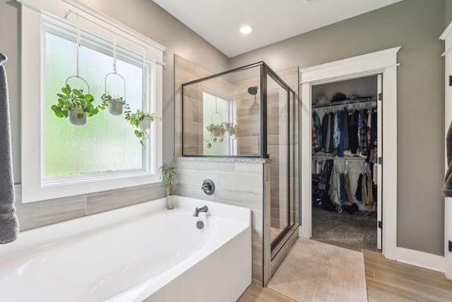 bathroom featuring a walk in closet, plenty of natural light, a stall shower, and a bath