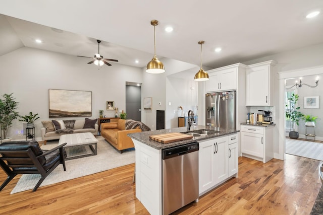 kitchen with a sink, stainless steel appliances, open floor plan, white cabinetry, and light wood-type flooring
