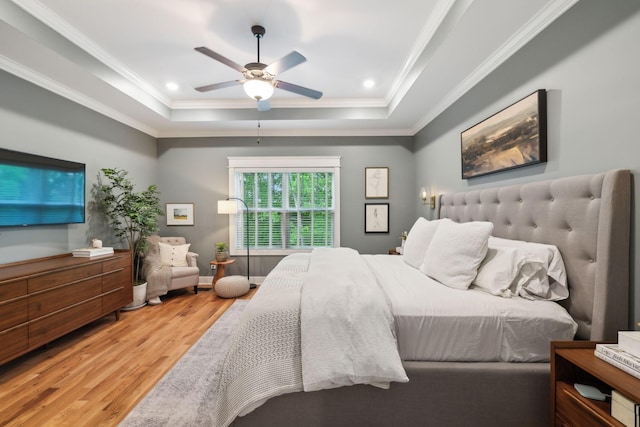 bedroom with ornamental molding, a ceiling fan, wood finished floors, and a tray ceiling