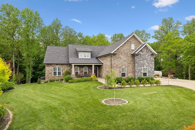 craftsman house featuring roof with shingles, a front yard, and brick siding
