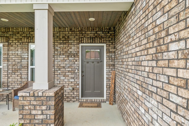 property entrance featuring brick siding and a porch